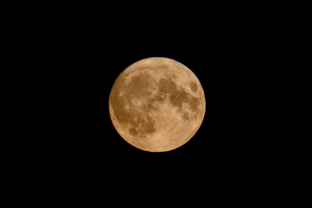 Detailed photograph of the full moon illuminated against a dark night sky.